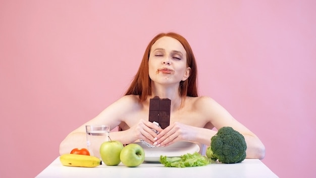 만족스러운 거식증 소녀는 탐욕스럽게 초콜릿을 먹는다. 섭식 장애. 신경성 식욕 부진증