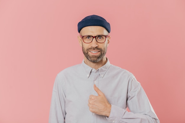 Satisfied attractive man has appealing look, raises thumb, agrees with something, smiles happily