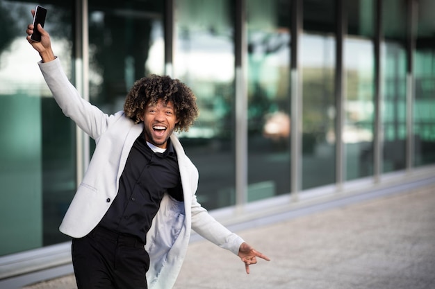 Photo satisfied black middle aged businessman dancing with happiness near office building outdoors free