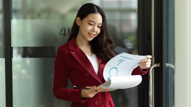 Satisfied businesswoman examines financial report papers compares paperwork or checks paper files