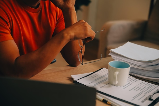 Satisfied caucasian successful guy freelancer or ceo relaxes at workplace with legs thrown on table Stylish guy uses laptop browses the Internet looks for ideas for a project sitting at the desk