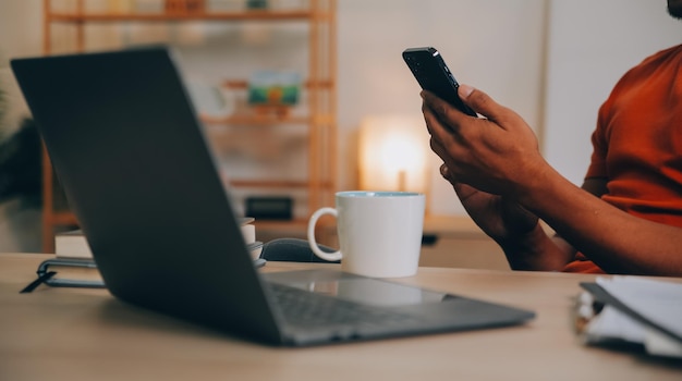 Satisfied caucasian successful guy freelancer or ceo relaxes at workplace with legs thrown on table Stylish guy uses laptop browses the Internet looks for ideas for a project sitting at the desk