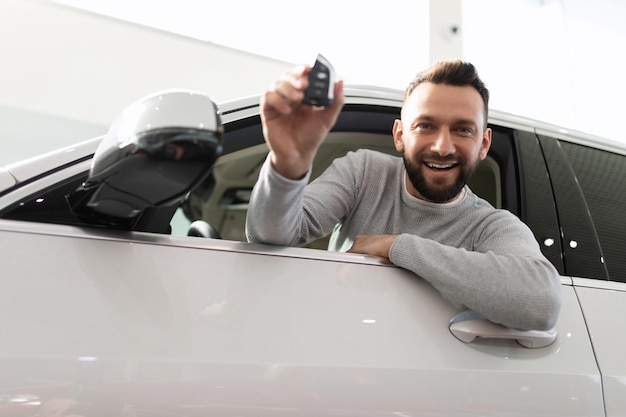 A satisfied customer looks out of the car with a key in his hands