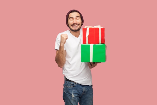 Satisfied extremely happy bearded man standing holding present box clenched fist celebrating