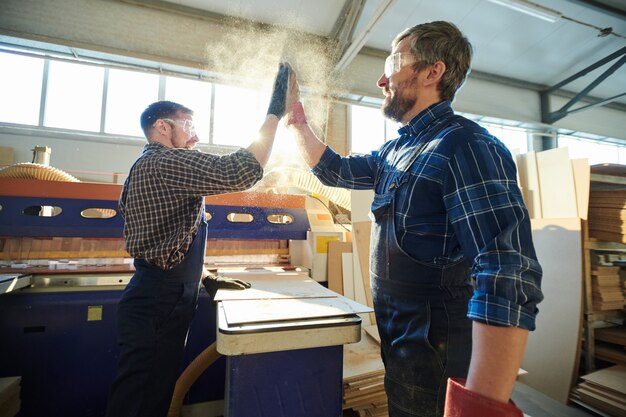 Photo satisfied factory workers making dusty high five