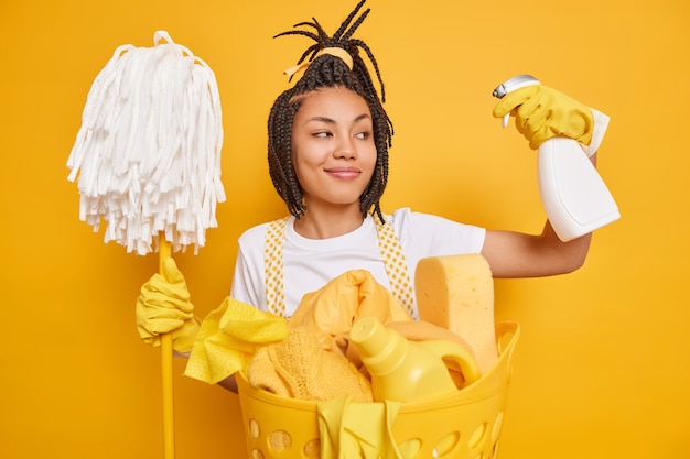 Satisfied female cleaner keeps cleaning detergent in hands mop