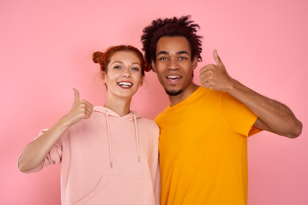 Photo satisfied ginger woman and african american man shows thumb up indicate sales discounts feel excited