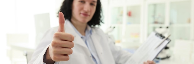 Satisfied male laboratory worker shows thumb up gesture looking in camera longhaired man smiles