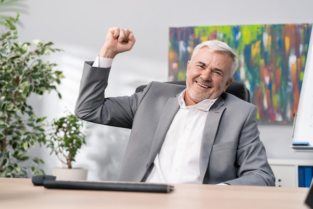 Satisfied man dressed in suit sits in front of computer\
received good news money in bank account