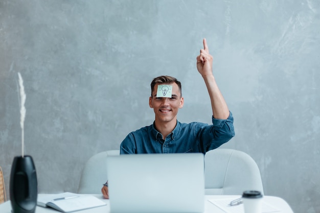 Satisfied man with raised hand thinking about good creative idea