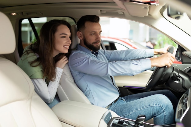 Satisfied married couple in a new car exploring the features of the interior