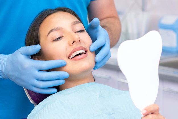 Довольный пациент у стоматолога. который демонстрирует свою безупречную улыбку после лечения в клинике