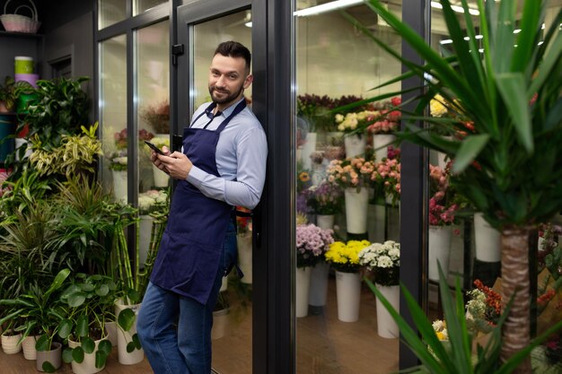 A satisfied professional florist in blue aprons next to the fridge of fresh flowers of luxury