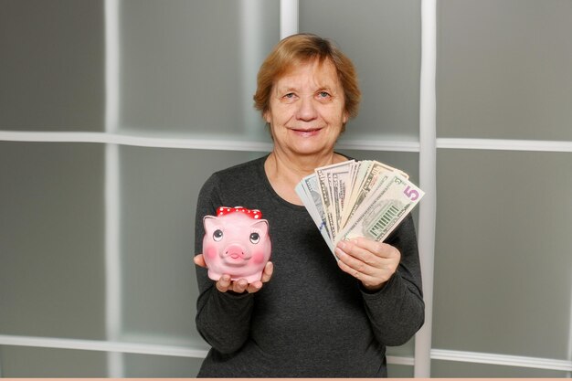 満足した高齢の女性が片手にゴミ箱をもう一方の手に紙幣を握っている SHOTLISTbanking