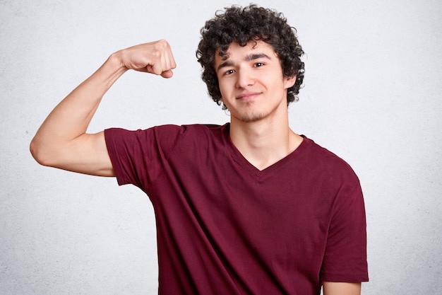 Satisfied strong man shows biceps or muscles