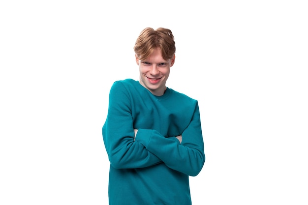 Satisfied student guy with red hair guy dressed in a blue sweater on a white background