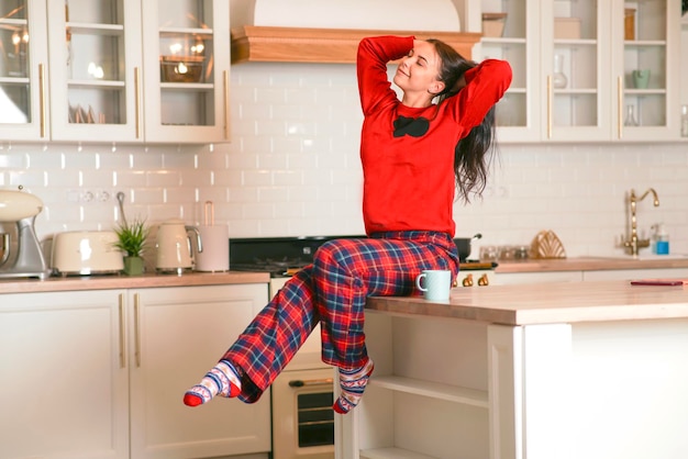 A satisfied sweet woman in the morning in the kitchen at home stretch and have a good mood