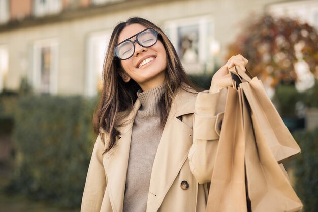 Foto cliente donna soddisfatta con un bel sorriso ampio che tiene sacchetti per lo shopping ecologico in strada