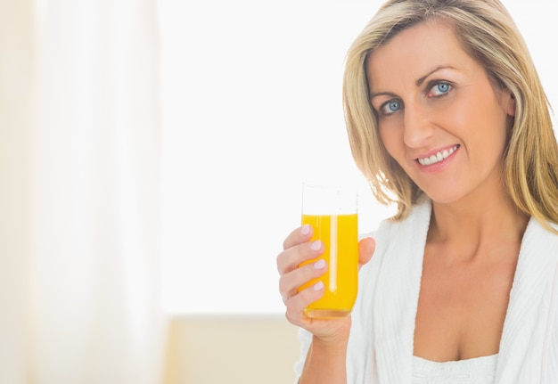 Satisfied woman looking enjoying a glass of orange juice