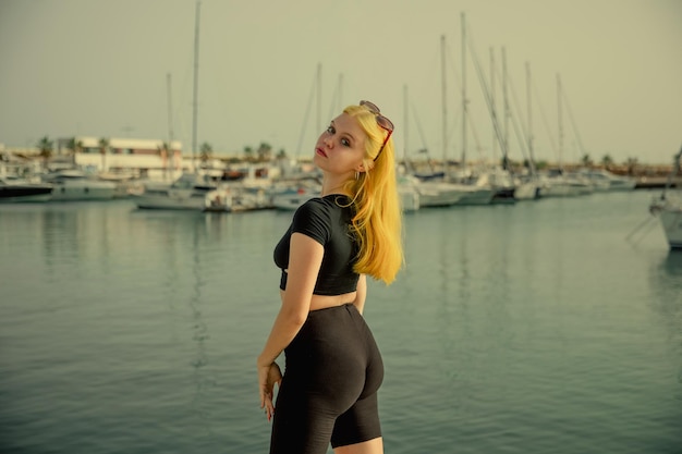 A satisfied woman relaxes by the sea against the background of yachts