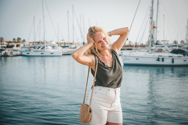 A satisfied woman relaxes by the sea against the background of yachts