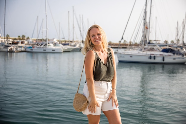 A satisfied woman relaxes by the sea against the background of yachts