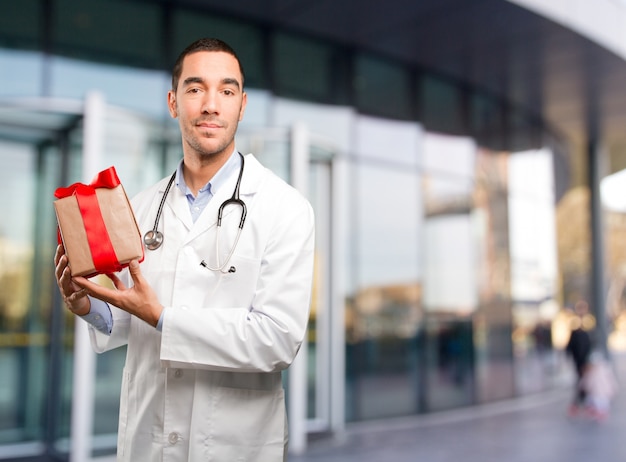 Satisfied young doctor holding a gift