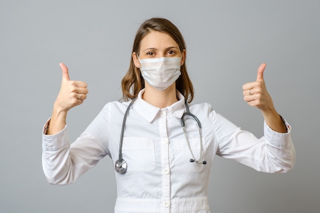 Satisfied young female doctor showing thumb up gesture isolated