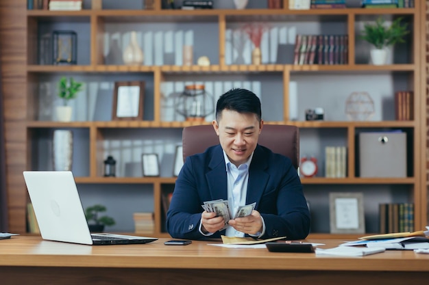 만족한 젊은 남자 아시아 회사원은 봉투 계산에 돈 급여 현금 보상을 받았습니다