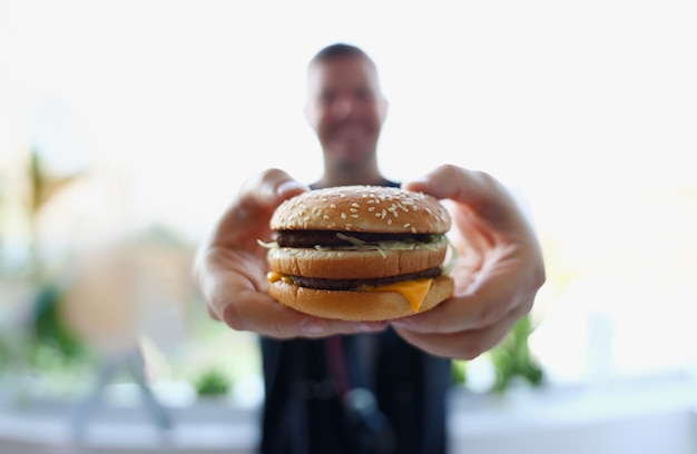 Photo satisfied young man holding a hamburger