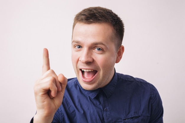 Satisfied young man showing index finger up giving advice or recommendation