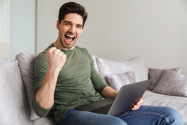 Satisfied young man using laptop computer