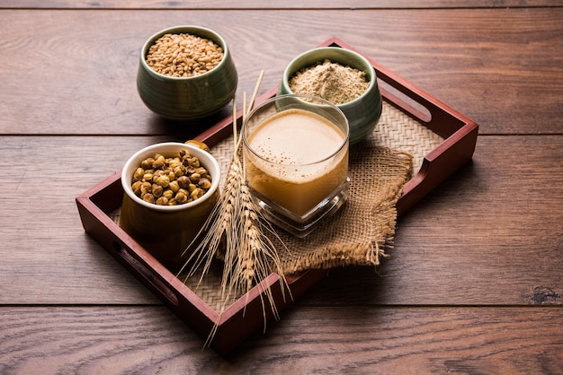 Sattu sharbat is a cooling sweet drink made in summer with roasted black chickpea flour, barley, suger, salt & water. served in a glass. selective focus