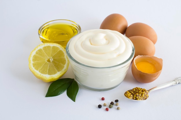 Sauce mayonnaise in the glass bowl on the white background Closeup