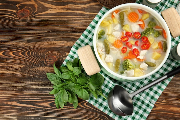 Saucepan with delicious turkey soup on wooden table