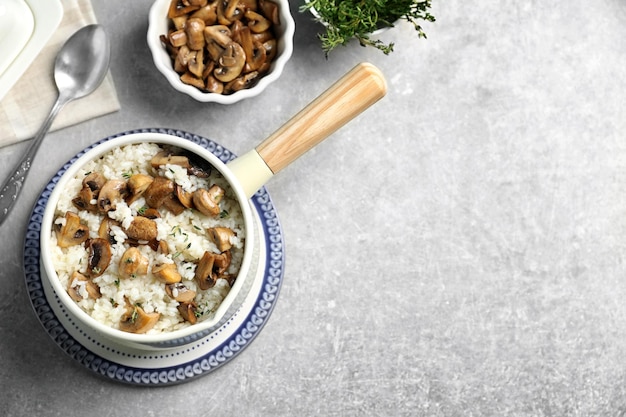 Saucepan with risotto and mushrooms on table