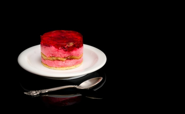 Foto piattino con torte e cucchiaino sul nero.