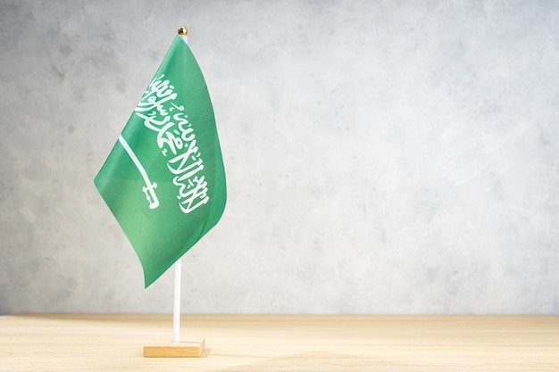 Saudi Arabia table flag on white textured wall. Copy space for text, designs or drawings