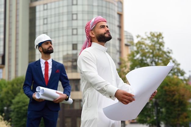 Saudi businessman going through the building plan with his architect waiting on the