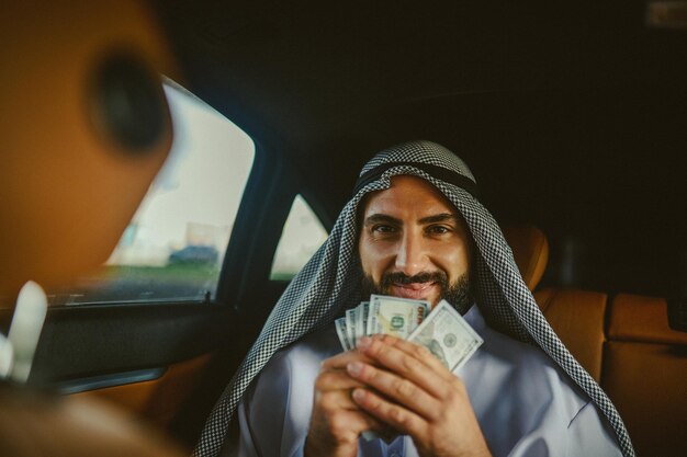 Saudi man in a traditional clothing in a car holding money