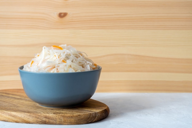 Sauerkraut in a gray bowl on a wooden board