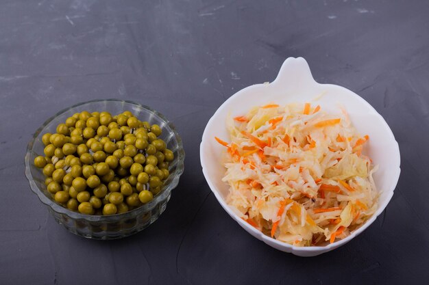 Sauerkraut and green peas on a gray background