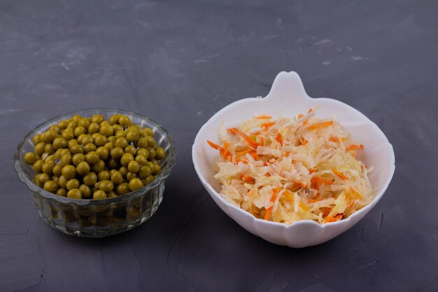 Sauerkraut and green peas on a gray background