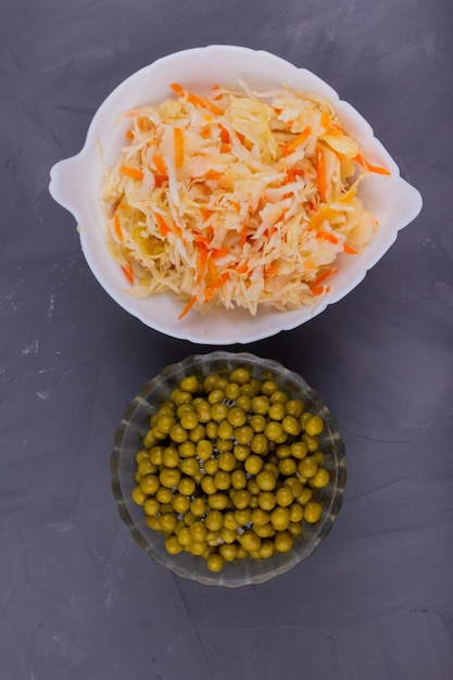 Sauerkraut and green peas on a gray background