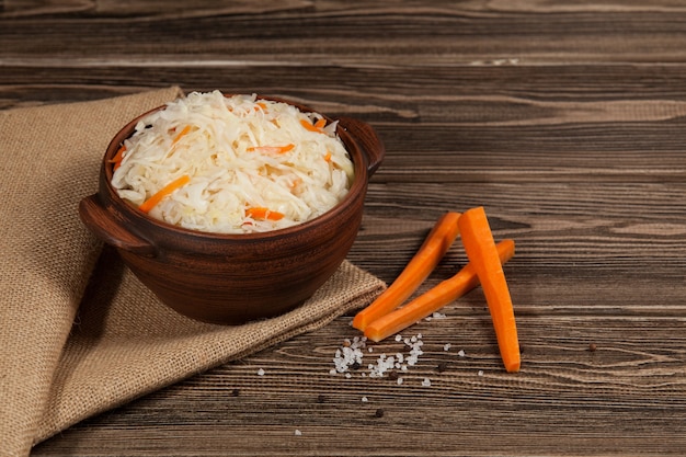 Sauerkraut with carrots in bowl on wooden