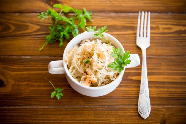 sauerkraut with carrots and spices in a bowl on a wooden table