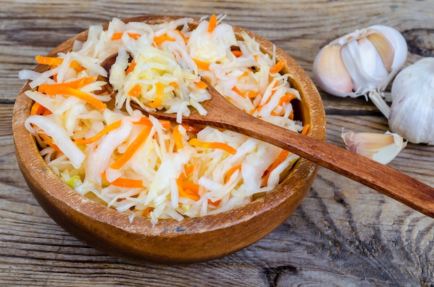 Sauerkraut with carrots in wooden bowl on table