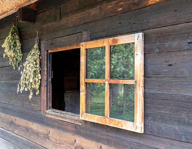 Sauna or bathhouse window of a village bath or sauna. Brooms on the wall.