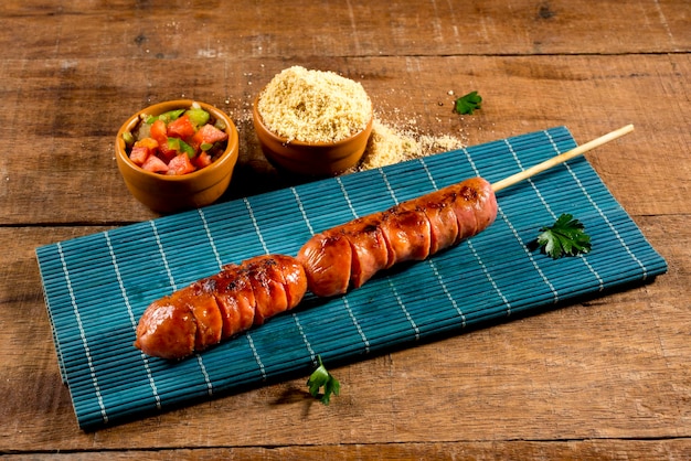 Sausage barbecue on a stick on wooden background churrasquinho\
de linguica