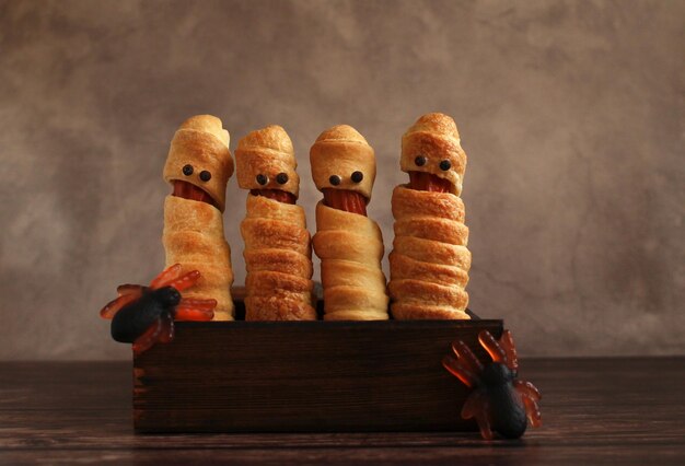 Sausage in the dough in the form of a mummy in a wooden box for the Halloween holiday